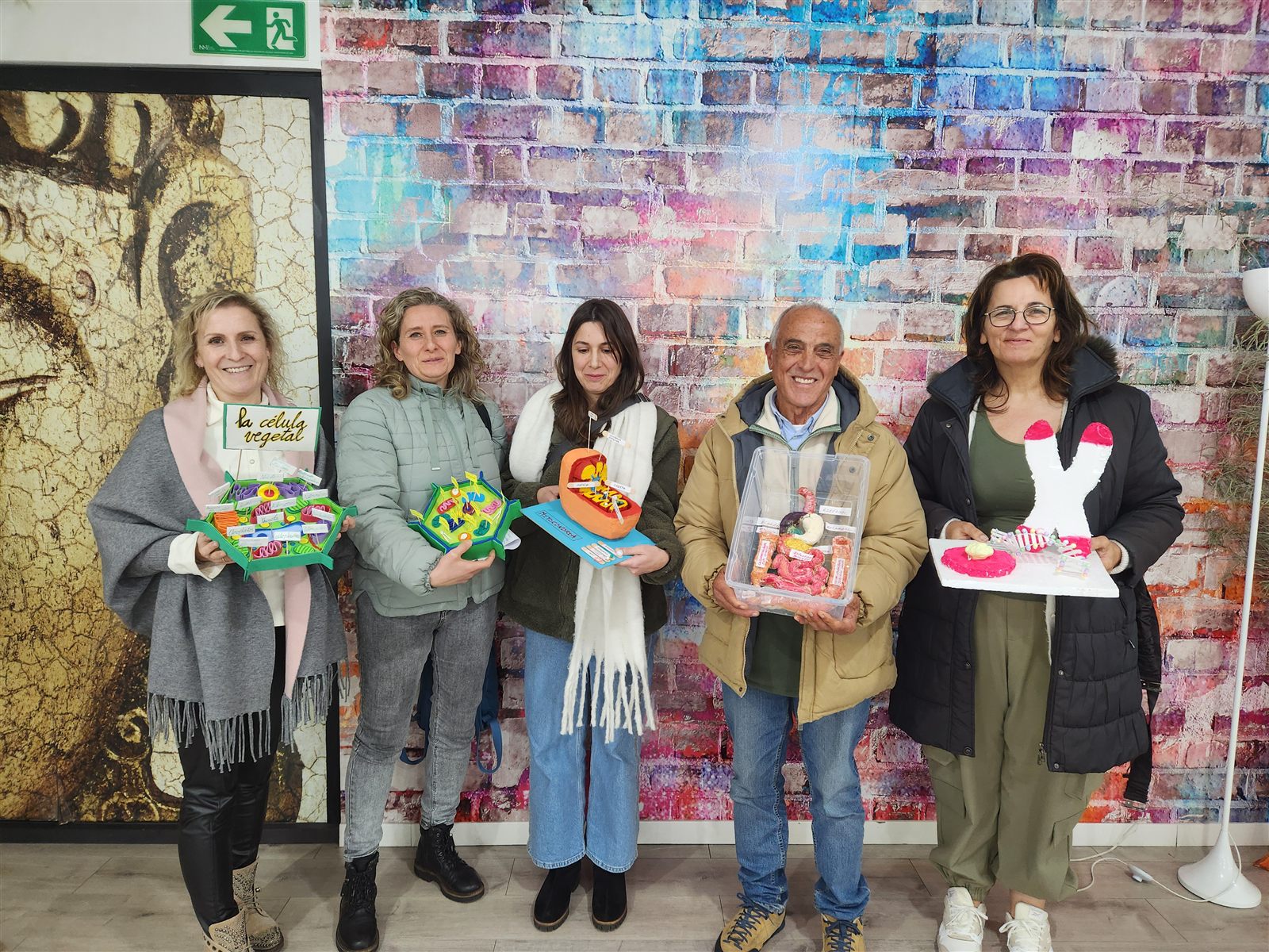 Estudiantes y docentes de EIDH sonríen juntos con sus trabajos