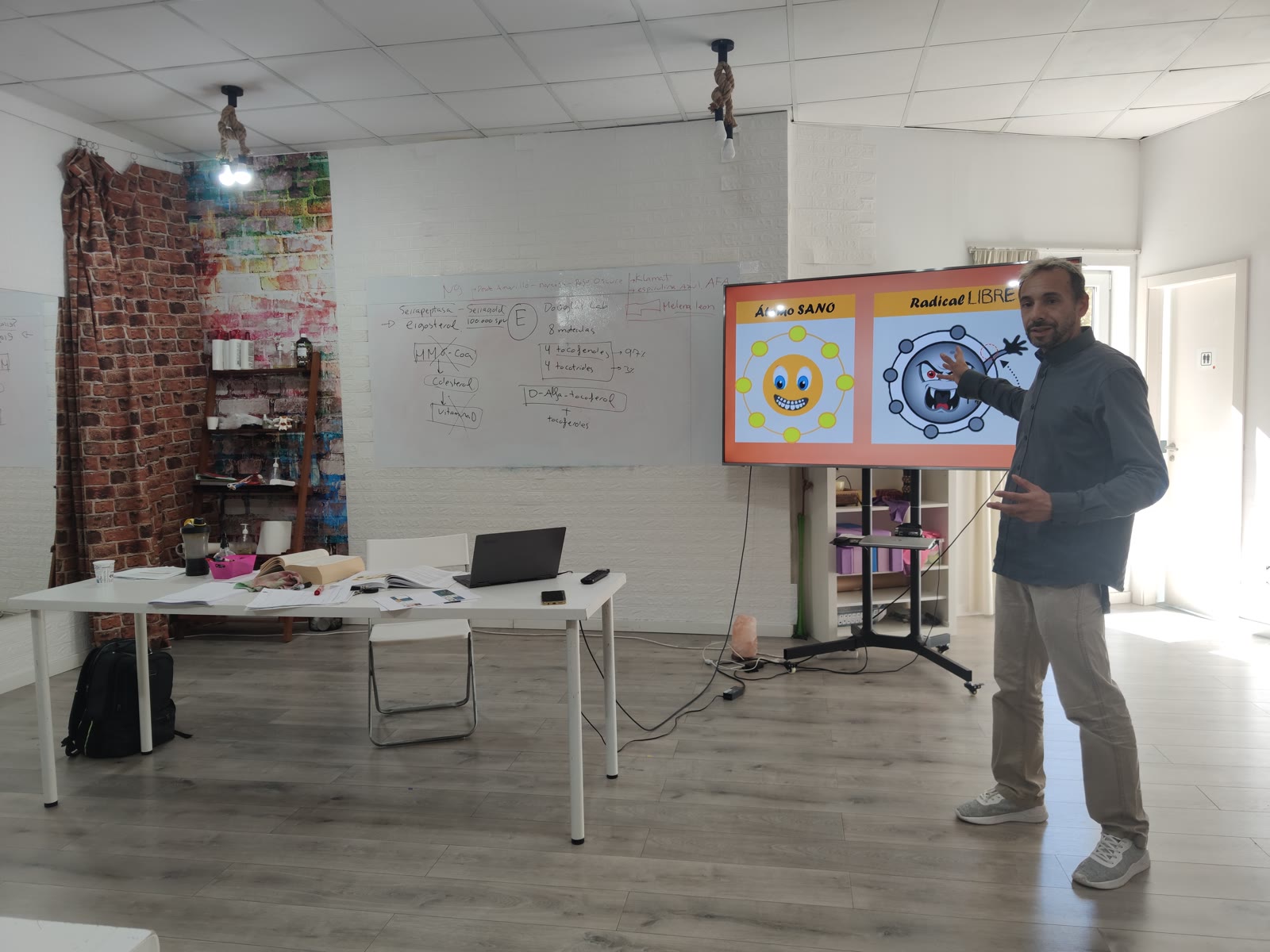 Profesor explicando un concepto delante de la pantalla y la pizarra